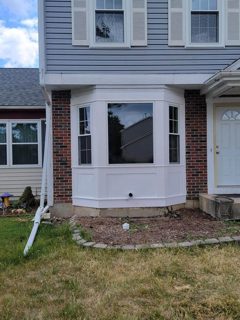 bay-window-installation-front-house Newly installed white bay window on the front of a two-story house with brick and siding exterior.