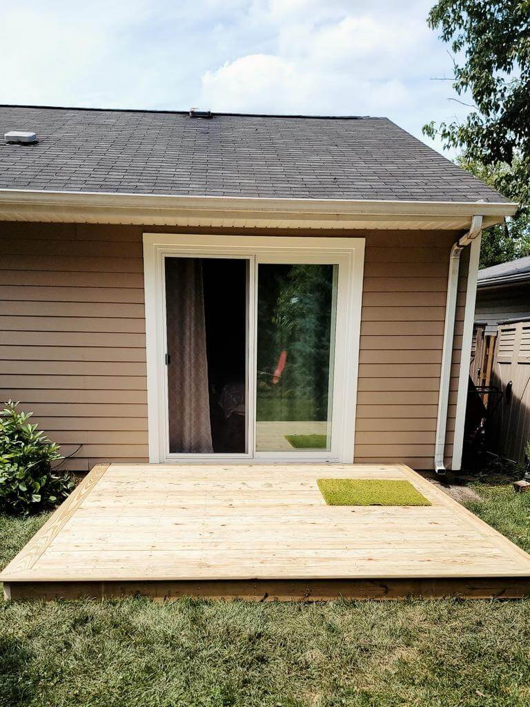 new-backyard-patio-deck Freshly built backyard wood deck with sliding glass door entrance and brown siding exterior.